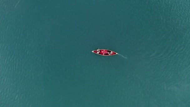 Een jonge man en een meisje varen op een roeiboot op het meer. — Stockvideo
