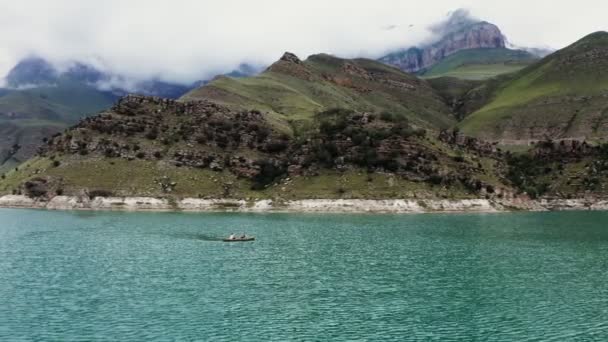 Мужчина и женщина плывут на лодке по озеру среди скалистых гор — стоковое видео