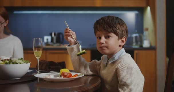 Snygg pojke äter sittandes vid ett festligt bord med sin familj på Thanksgiving — Stockvideo