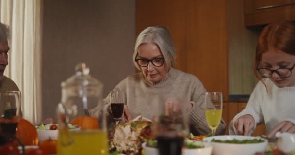 家族は感謝祭の日のセットテーブルに座って、お祝いの夕食を食べています — ストック動画