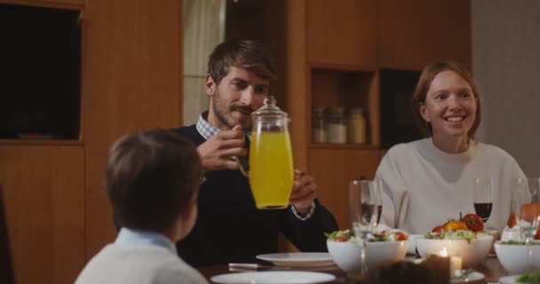 Um homem de aparência europeia derramando suco de um decantador em um copo para chil — Vídeo de Stock