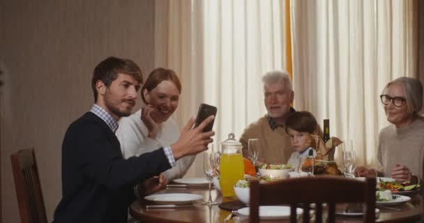 Rodina bere selfie na telefon sedí u prostřeného slavnostního stolu, na Díkůvzdání — Stock video