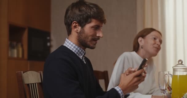 Een jongeman begint een video gesprek op zijn mobiel de hele familie sluit zich bij hem aan — Stockvideo