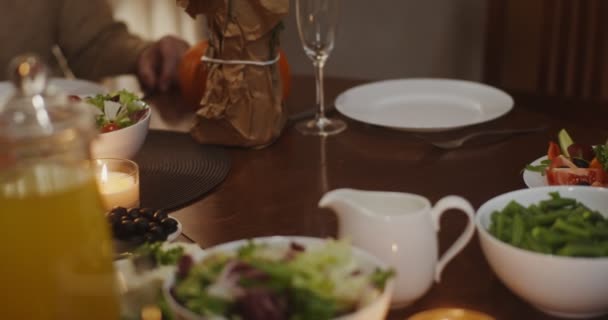 Egy nő egy sült pulykát tesz egy ünnepi asztal közepére. — Stock videók