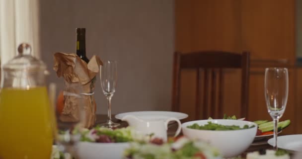 Een vrouw plaatst een geroosterde kalkoen in het midden van een feestelijk gedekte tafel — Stockvideo