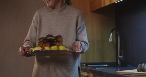 Una mujer coloca un pavo asado en el centro de una mesa festiva — Vídeo de stock