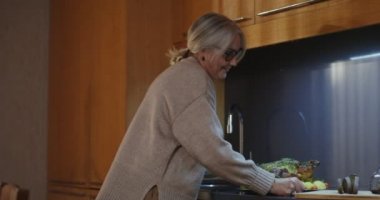 Bir kadın kızarmış hindiyi şenlikli bir masanın ortasına koyar.