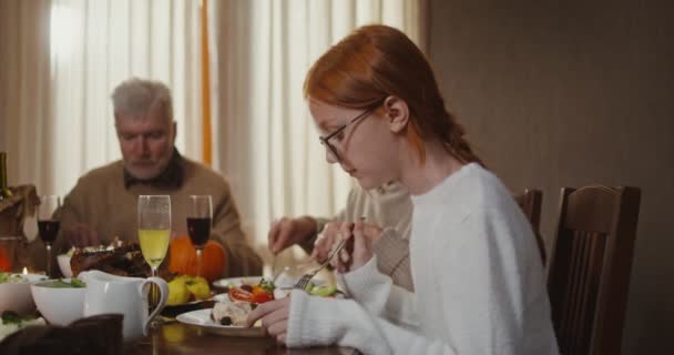Beautiful young red-haired girl eating a festive dinner with her family — Stock Video