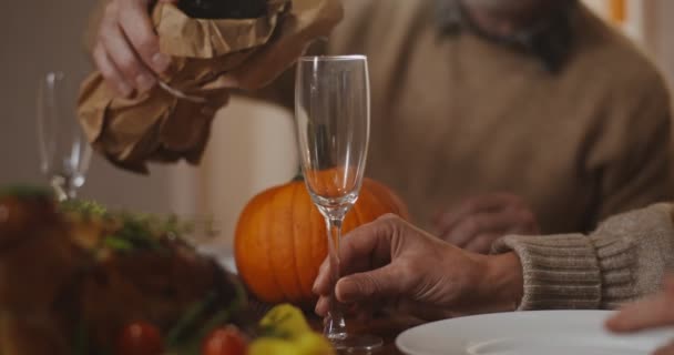 Un homme aux cheveux gris verse du vin d'une bouteille dans un verre, gros plan — Video