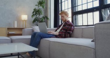 Genç bir adam dizüstü bilgisayarını bitiriyor, esniyor ve cep telefonunu alıyor.