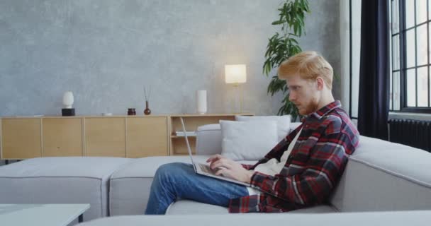 Ein junger Mann beendet die Arbeit an einem Laptop, schließt ihn und geht — Stockvideo