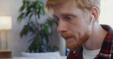 Kulaklıklı yakışıklı adam gülümsüyor, bilgisayardan video görüşmesi yapıyor.