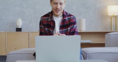 Kulaklıklı yakışıklı adam gülümsüyor, bilgisayardan video görüşmesi yapıyor.