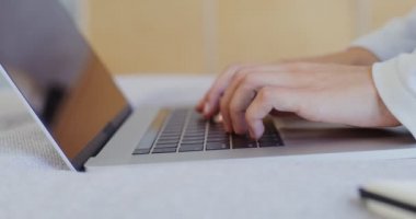 Bir kadın dizüstü bilgisayarında oturuyor ve yanında bir defter var.