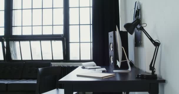 Een jonge vrouw in casual kleding komt naar de computer, gaat zitten en begint te werken — Stockvideo