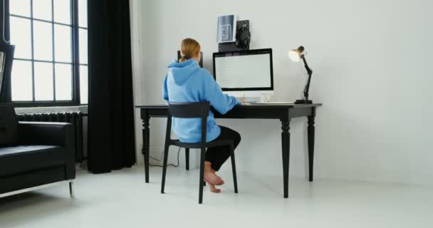 평상복을 입은 한 젊은 여자 가집에서 일하는 동안 컴퓨터를 사용 한다 — 비디오