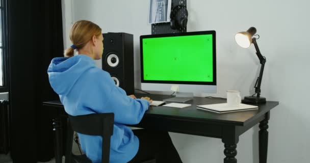 Eine junge Frau in Freizeitkleidung tippt von zu Hause aus am Computer — Stockvideo