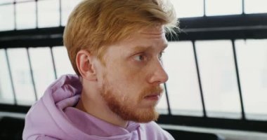 Genç kızıl saçlı, sakallı ve çilli bir adam önünde duruyor.