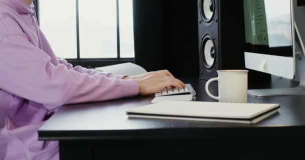 En man klädd i avslappnade kläder skriver sitter vid datorn i modern inredning — Stockvideo