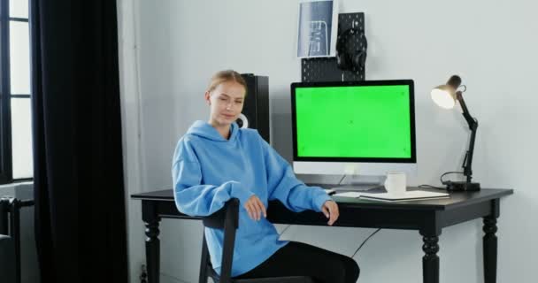 Young woman smiling looking at the camera sitting in front of a green monitor — Stock Video