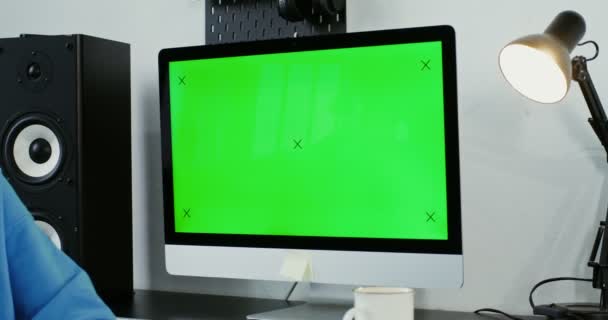 Mujer joven sonriendo mirando a la cámara sentada frente a un monitor verde — Vídeos de Stock