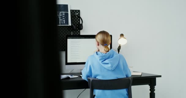 Junge Frau nutzt das Internet, während sie vor einem Computerbildschirm sitzt — Stockvideo