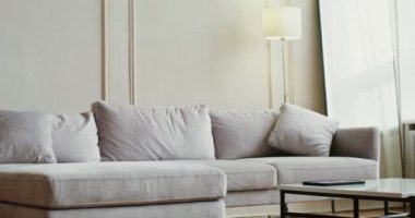 Gündelik giysiler içinde genç bir kadın kanepeye oturup tablet kullanmaya başladı.