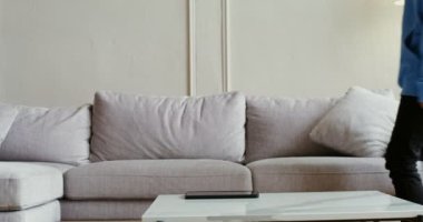 Gündelik giysiler içinde genç bir kadın kanepeye oturup tablet kullanmaya başladı.