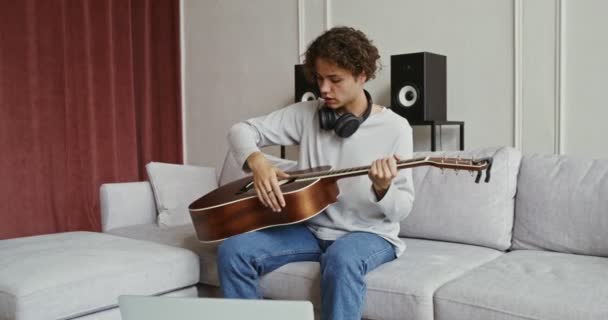 Een man kijken gitaar tutorial op laptop en leren instrument spelen — Stockvideo