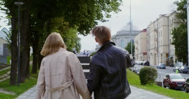 Stijlvolle jongen en meisje lopen rond in de stad, hand in hand en praten. — Stockvideo