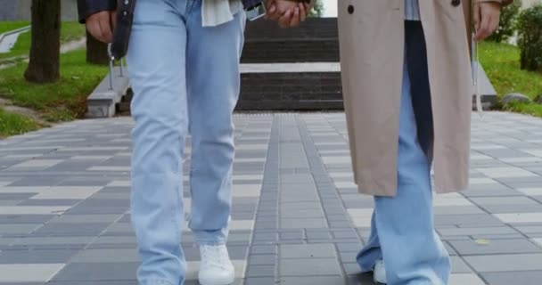 Stylový chlap a holka se procházejí po městě, drží se za ruce a mluví — Stock video