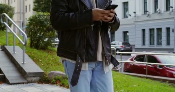 A young man uses the phone while walking around the street of the autumn city — Stock Video