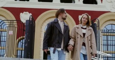 Genç çift merdivenlerden inip el ele tutuşur, konuşur ve güler.