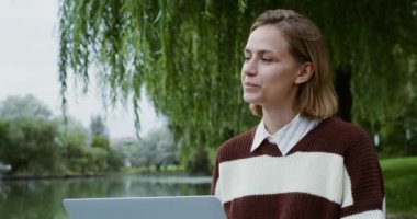 Genç bir kız kaldırımda dizüstü bilgisayar kullanıyor.