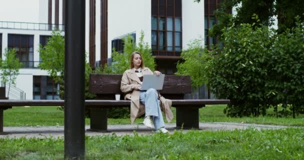 Une jeune femme finit de travailler sur un ordinateur portable, le ferme et part, buvant du café — Video