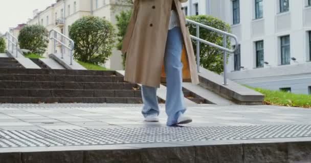 Una giovane donna guarda nel cellulare e sorride, camminando lungo la strada della città — Video Stock