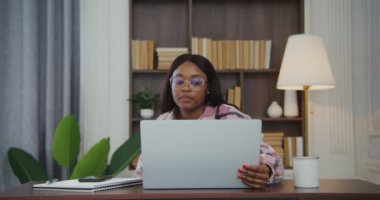 Afrikalı Amerikalı bir kadın bir dizüstü bilgisayarın kapağını açar ve bir video görüşmesi başlatır.