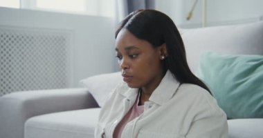 Afrikalı Amerikalı bir kadın yerde otururken dizüstü bilgisayarda yazıyor.