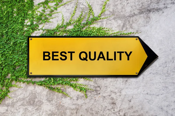 Best quality on yellow sign hanging on ivy wall — Stock Photo, Image