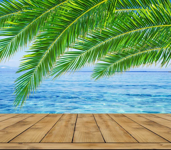 Голубое море, пальмовый лист и деревянная терраса — стоковое фото