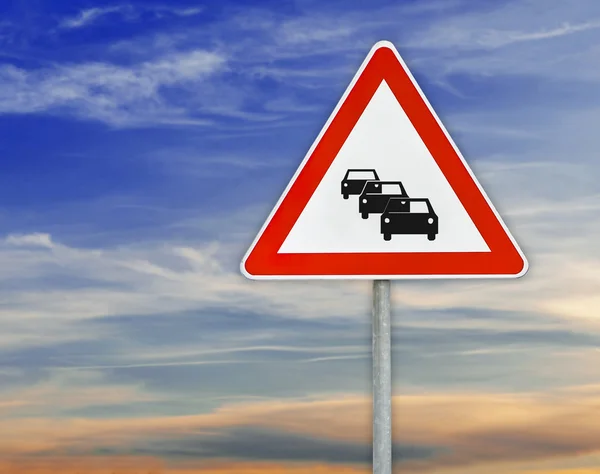 Segitiga tanda jalan mobil pada batang dengan langit mendung — Stok Foto