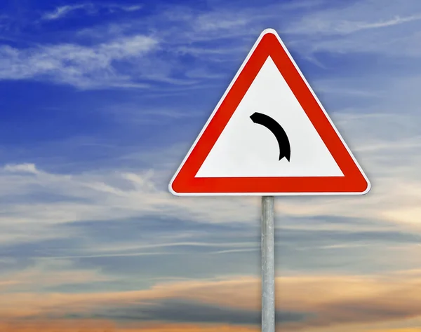 Triangle road sign left turn on rod with cloudy sky — Stock Photo, Image