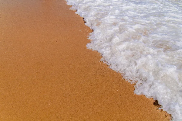 Небольшая пенная волна на море рядом с пляжем — стоковое фото