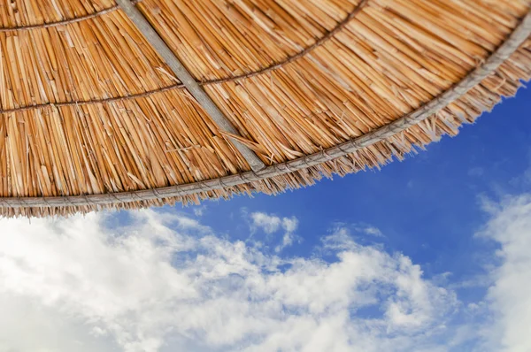 Солом'яна парасолька на тлі блакитного хмарного неба — стокове фото