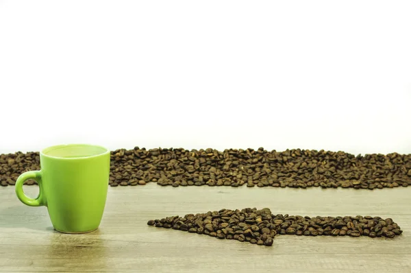 Seta dos grãos de café com uma xícara de bebida em fundo de madeira — Fotografia de Stock