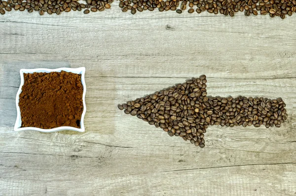 Seta dos grãos de café com uma xícara de café moído fresco em fundo de madeira — Fotografia de Stock