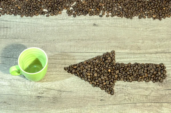 Seta dos grãos de café com copo vazio de bebida em fundo de madeira — Fotografia de Stock