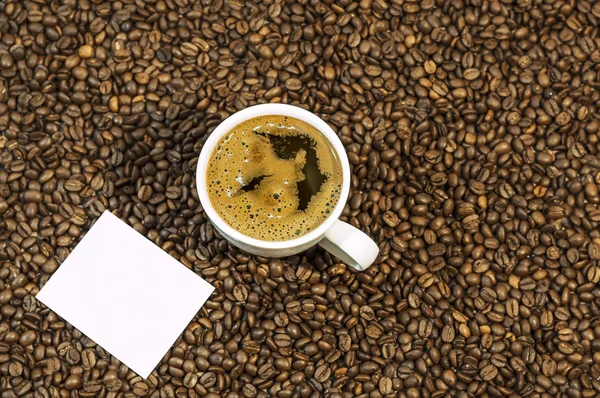 Fundo de grão de café com xícara de café quente fresco e espaço para texto na mesa da cozinha — Fotografia de Stock