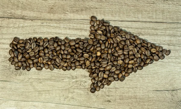 Grãos de café na forma de setas sobre fundo de madeira — Fotografia de Stock