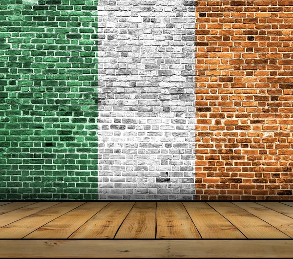 Drapeau irlandais peint sur un mur de briques avec plancher en bois — Photo